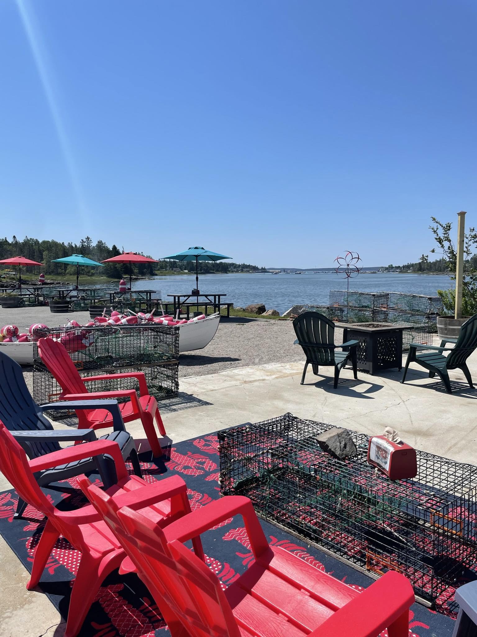 Colorful Adirondack chairs, lobster traps, picnic tables, and waterfront seating overlooking Bass Harbor at Archie’s Lobster.